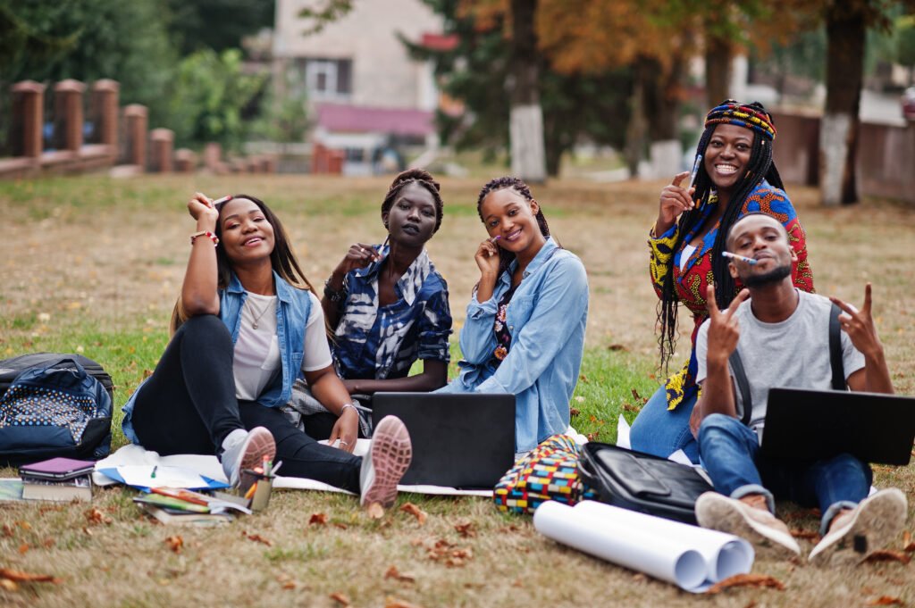Group Five African College Students Spending Time Together Campus University Yard Black Afro Friends Sitting Grass Studying With Laptops 1024x681